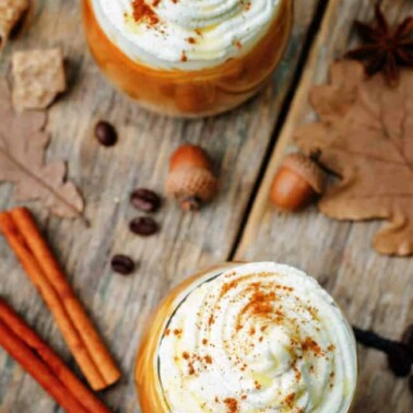 Two cups of Pumpkin Pie Hot Chocolate with fall themed decorations on the table.