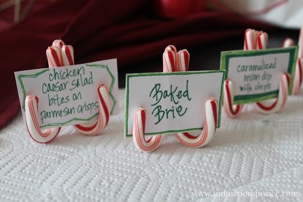 Miniature candy canes resting upside down holding cards with text on them.