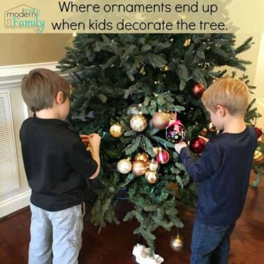 Two boys decorating a Christmas tree with text above them.