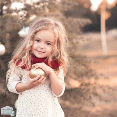 A little girl posing for a picture holding a golden ornament.