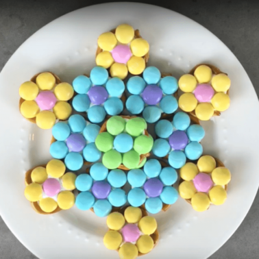 Colorful candies shaped into a flower sitting on a white plate.