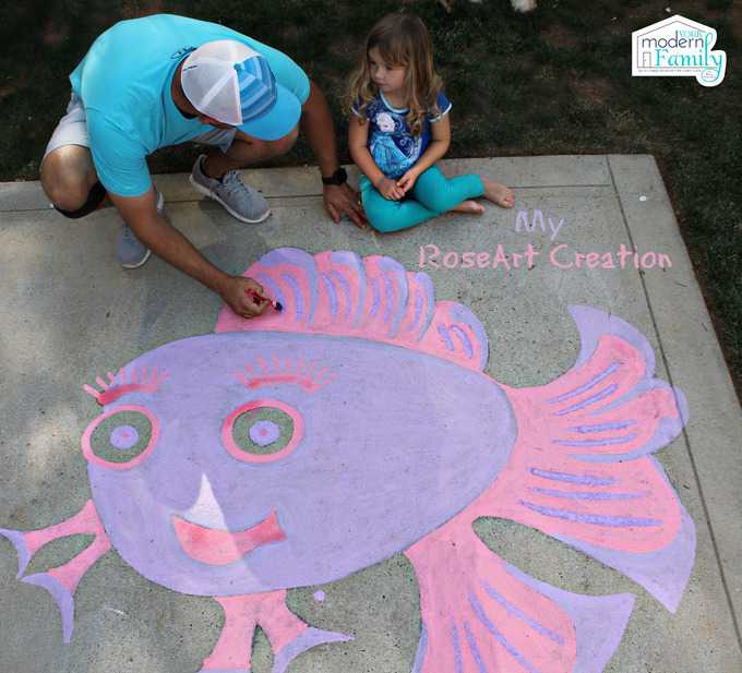 A little girl and her dad drawing with chalk on the driveway.