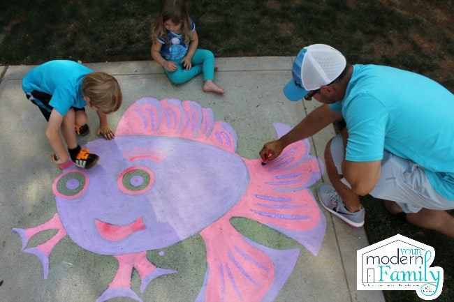 A family coloring with chalk on the driveway.