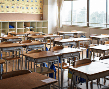 A picture of a school classroom with desks and chairs.
