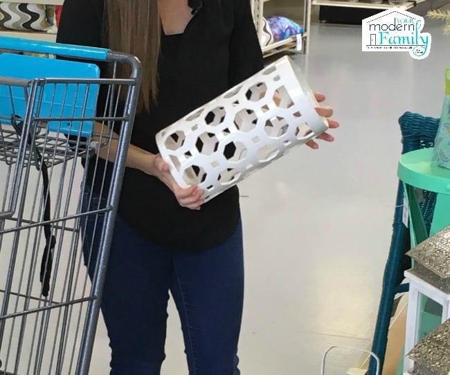 A person standing beside a shopping cart holding a white ceramic vase.