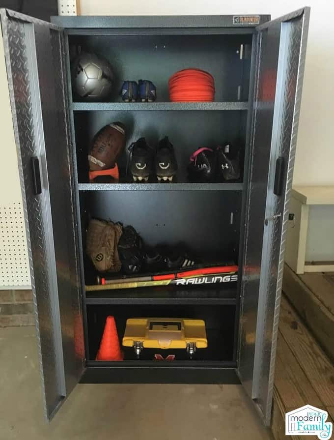 An open metal cabinet with a variety of sporting equipment neatly organized.