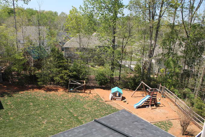 Aerial view of a back yard with a swing set and a slide.