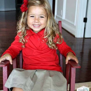 A little girl sitting in a child's rocking chair.