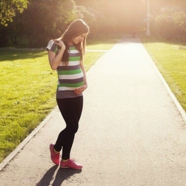 A pregnant woman standing on a sidewalk.