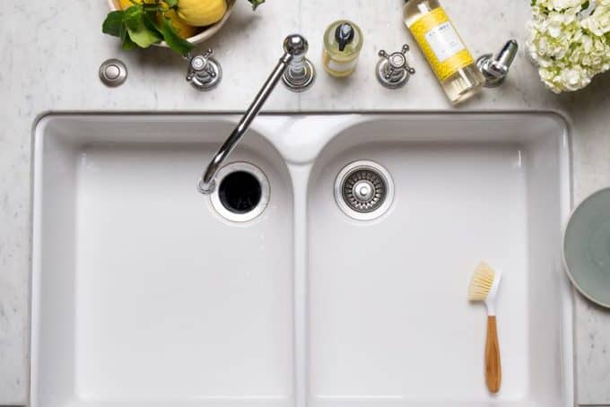 A top view of a kitchen sink with bottles of cleaner on the counter.