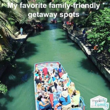A tour boat filled with people on a man made river with text above them.