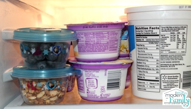 A view of the inside of a refrigerator with Glad containers filled with food sitting beside yogurt.