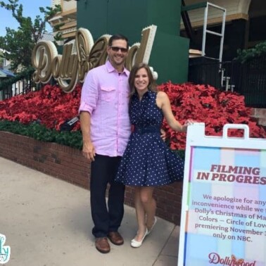 A couple standing in front of a sign in Dollywood.