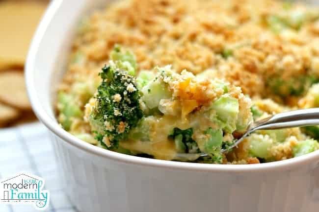 A casserole dish with a spoonful of broccoli and melted cheese. 