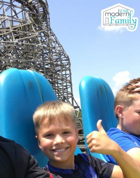 A young boy smiling on a roller coaster ride.
