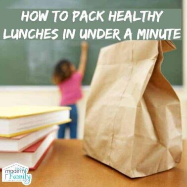 A brown bag lunch with a stack of books beside it and a child writing on a chalk board in the background with text on it.