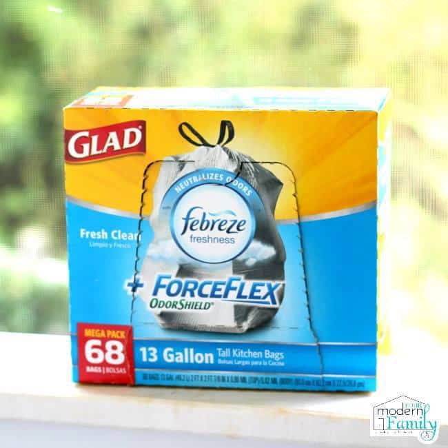 A box of Glad ForceFlex garbage bags on a porch railing.