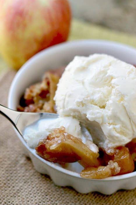A cup of apple cobbler with ice cream.