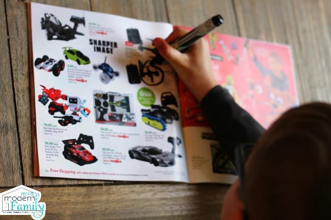 A boy circling a toy with a marker in a toy catalog.