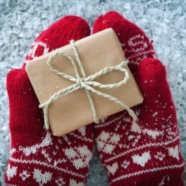 A small wrapped present resting in mittens.