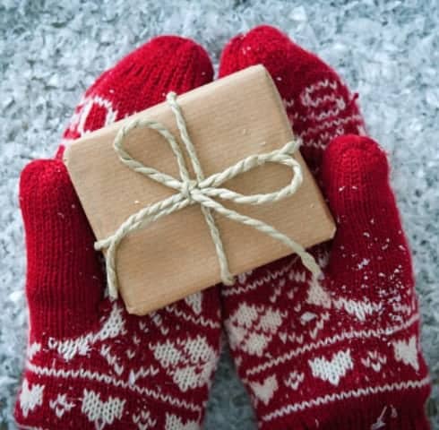 A small wrapped present resting in mittens.