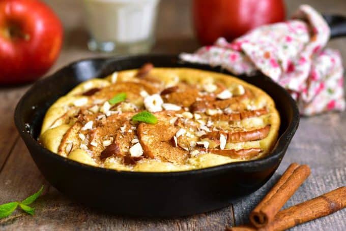 Rustic apple pancake in a skillet pan on a wooden background.