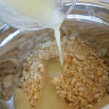 A close up of milk being poured into a bowl of ingredients.