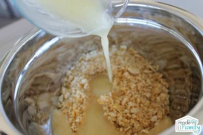 A close up of milk being poured into a bowl of ingredients.