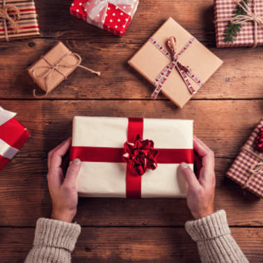 Numerous wrapped presents on a wooden table.