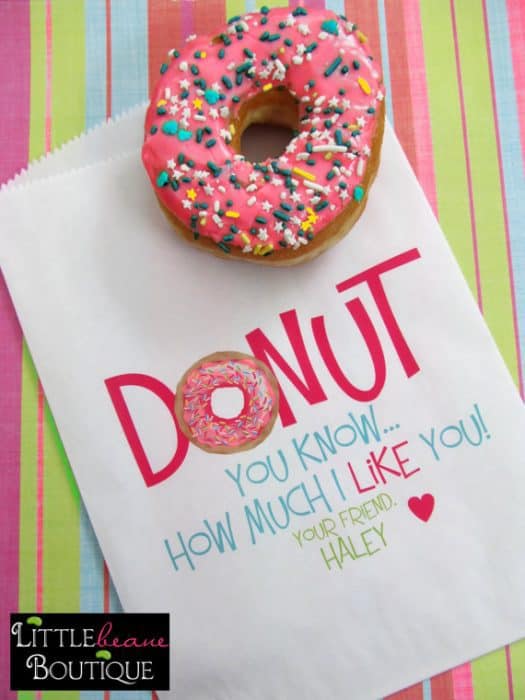 A donut sitting beside a Valentine card.