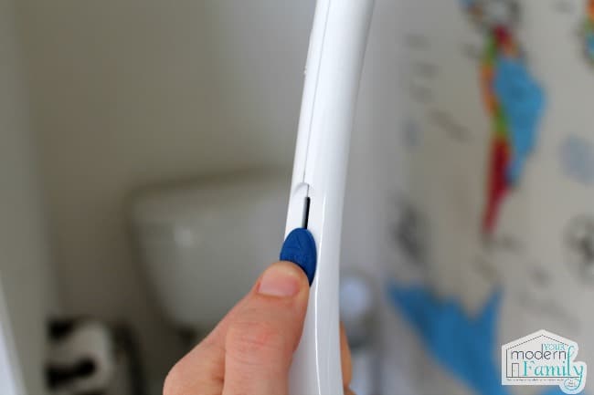 A close up of a person holding a toilet brush handle with a blue release button.