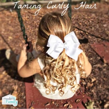 A view from behind of a little girl swinging on a swing.