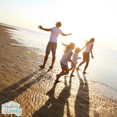 A man, a woman  and two children walking down a sandy beach.