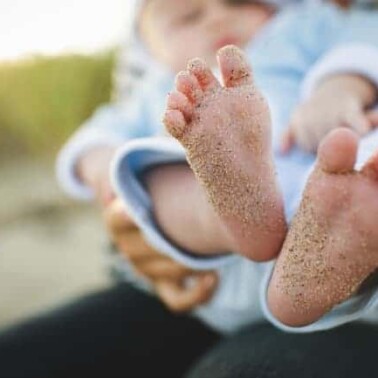 Picture of the bottoms of a baby's feet covered with sand.