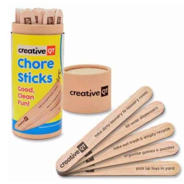 A container of Chore Sticks with a few sticks resting beside it.