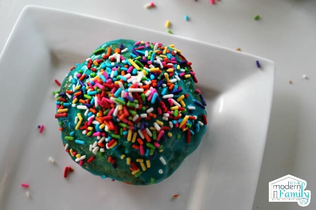 A cupcake decorated with blue icing and colorful sprinkles.