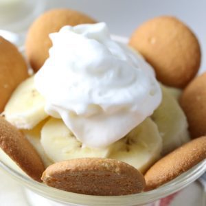 A bowl with cut bananas and vanilla wafers and topping.
