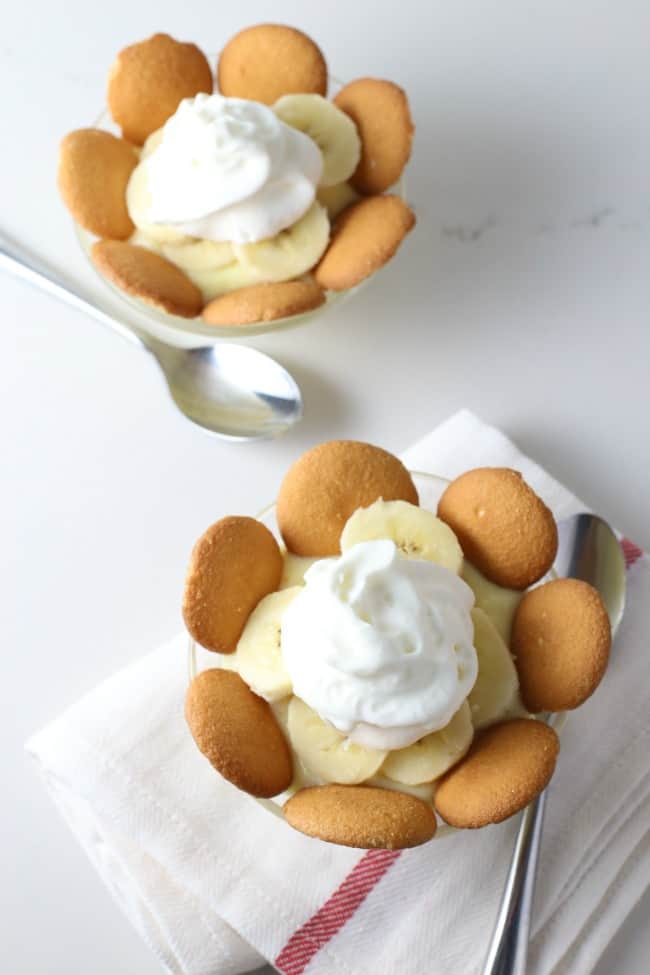  Banana pudding in cups with cut bananas and cookie wafers.