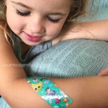 A close up of a girl with a band-aid on her arm.