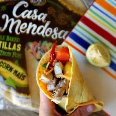 A soft shelled taco with a lemon beside it.
