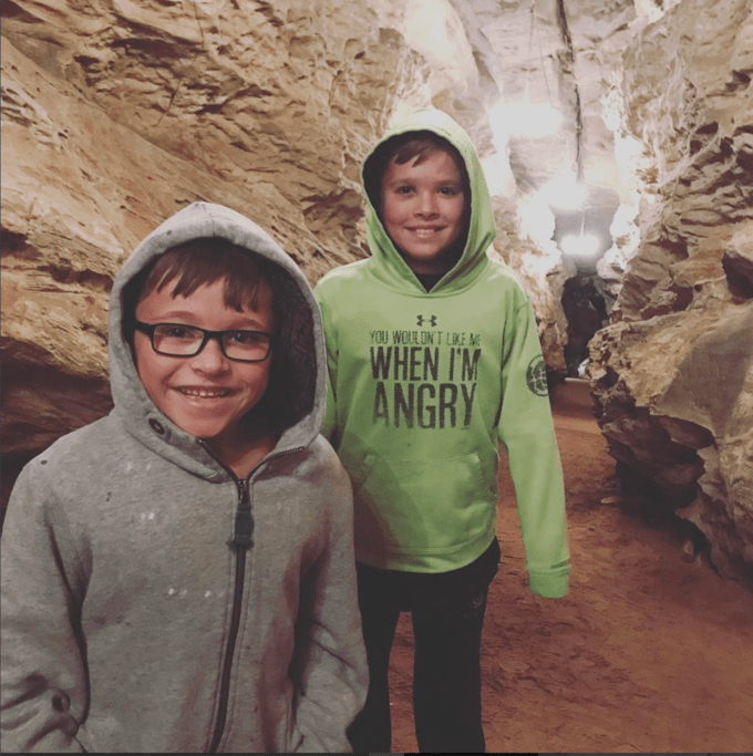 Two boys posing for a picture in a rock cave.