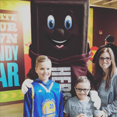 A group of people posing for the camera in front of a giant Hershey Bar.