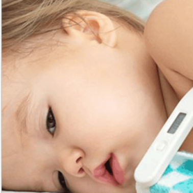 A sick baby lying down with a thermometer beside her.