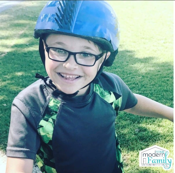 A little boy wearing a blue bike helmet.