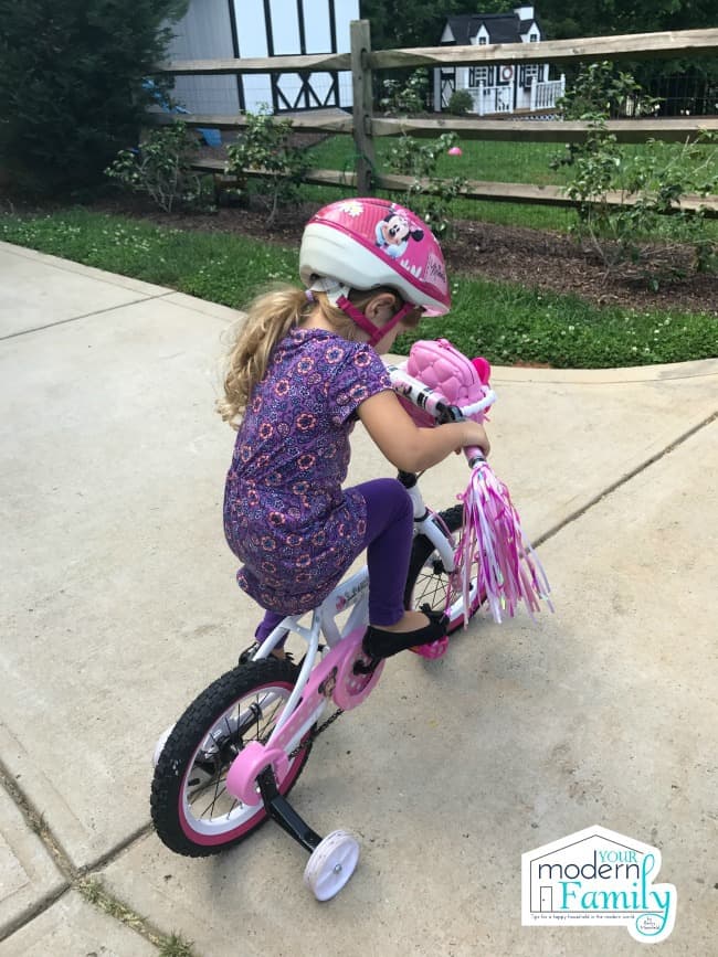 A little girl riding a bicycle.