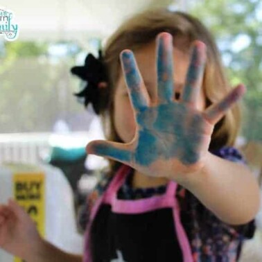 A little girl showing that her hand is painted blue.