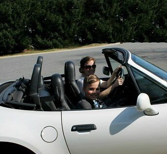 A woman and boy sitting in a convertible car.