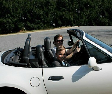 A woman and boy sitting in a convertible car.