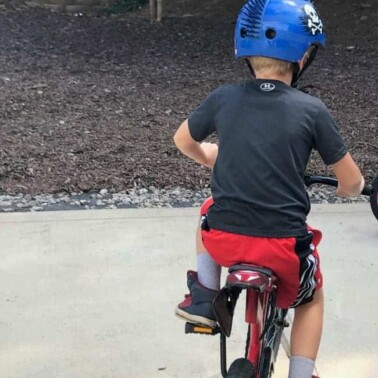 A little boy wearing a helmet while riding a bike.