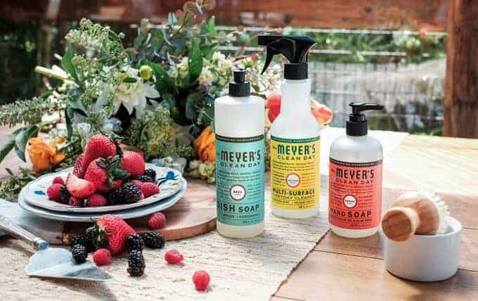 Three bottles of Meyer\'s cleaning products with a plate of fruit sitting beside them.